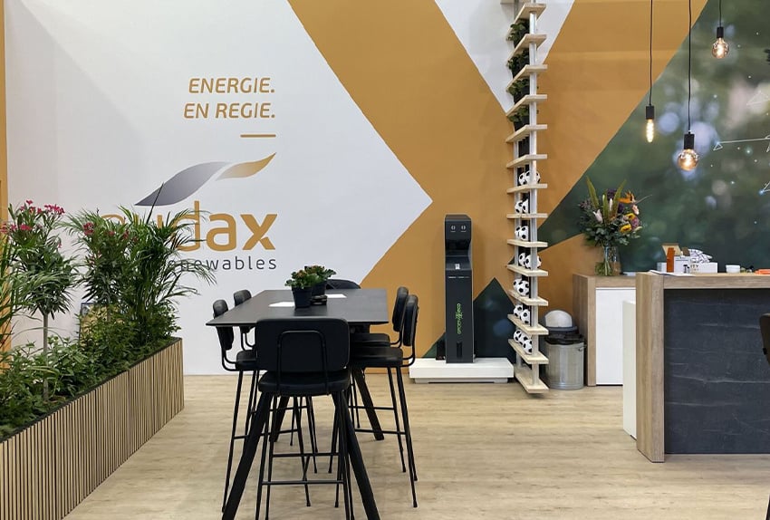 Moderne beursstand van Audax met duurzame aankleding, planten, zitgelegenheid en de slogan 'Energie. En regie.' op de wand.