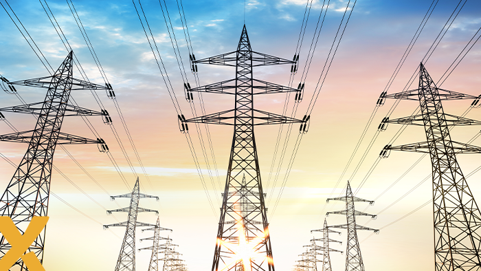 Hoogspanningsmasten met elektriciteitskabels tegen een zonsondergang.