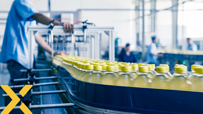 Productielijn in een fabriek waar kunststof flessen met gele doppen over een transportband worden verwerkt door medewerkers