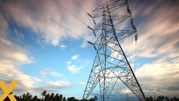 Hoogspanningsmast in een landelijk gebied onder een bewolkte maar heldere hemel, symbool voor elektriciteitsnet en energie-infrastructuur.
