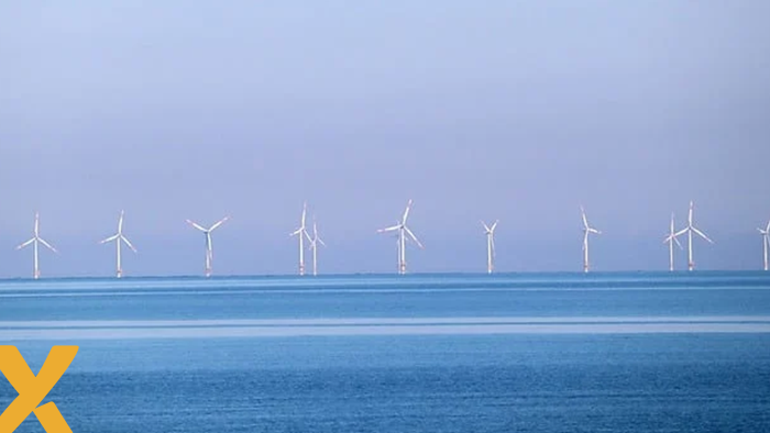 Windmolens op zee bij kalm wateroppervlak onder een heldere lucht.