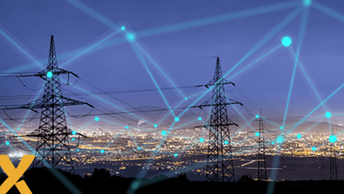 Hoogspanningsmasten voor een verlichte stad bij nacht, met digitale netwerkverbindingen als overlay, symbool voor een slim elektriciteitsnet.