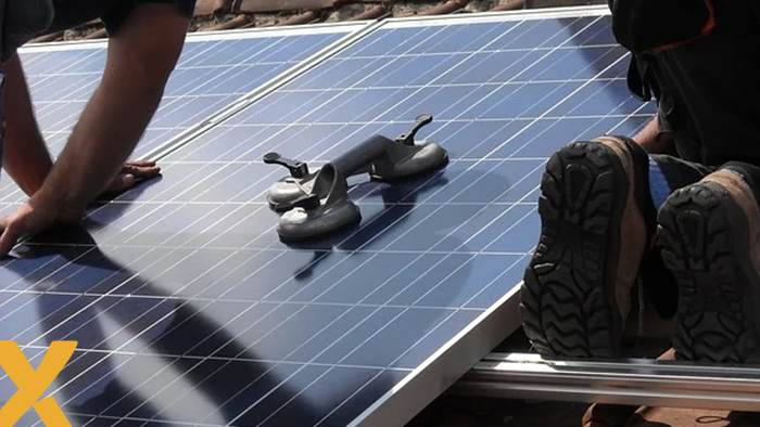 Monteurs installeren zonnepanelen op een dak met behulp van zuignappen.