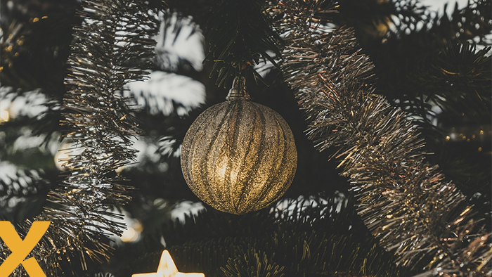 Close-up van een kerstbal en glinsterende slinger in een versierde kerstboom, symbool voor de feestdagen.