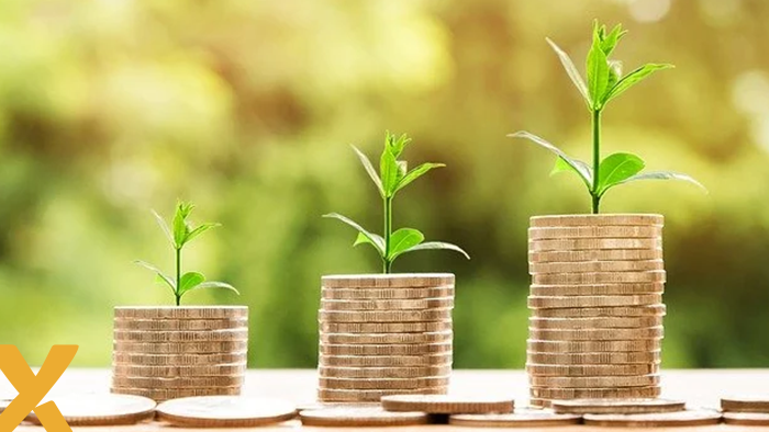 Stapels muntgeld met groeiende plantjes erbovenop als symbool voor financiële groei door energiebesparing.