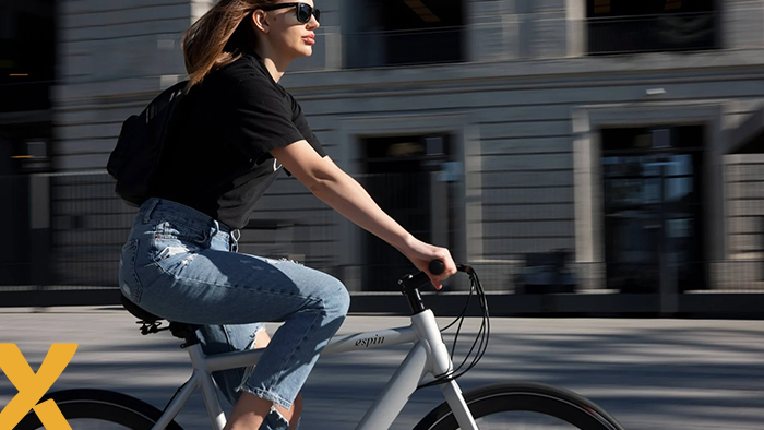 Vrouw fietst op een elektrische fiets door de stad op een zonnige dag.