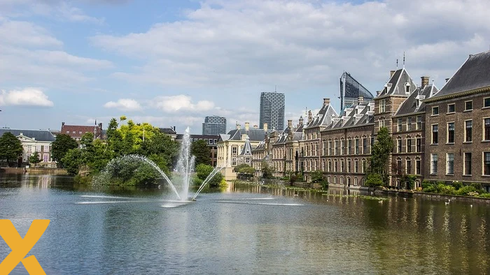 Het Binnenhof in Den Haag met de Hofvijver op de voorgrond en moderne hoogbouw op de achtergrond, symbool voor Nederlandse politiek en besluitvorming.
