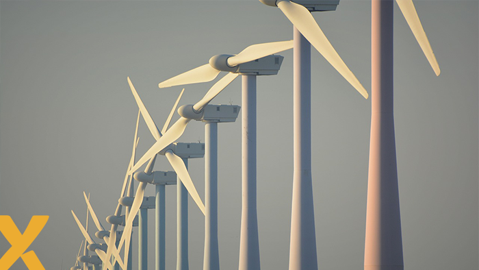 Rij windturbines op zee bij zonsopkomst, illustratief voor de overstap naar een emissievrij elektriciteitssysteem.