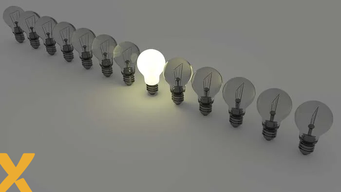 Rij gloeilampen waarvan er één brandt, symbool voor energieopslag, innovatie of oplossingen binnen het elektriciteitsnet.
