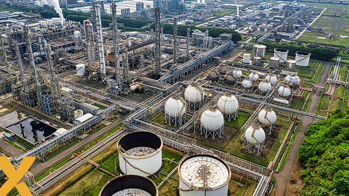 Luchtfoto van een groot gas- of chemisch industriecomplex met opslagtanks en pijpleidingen.