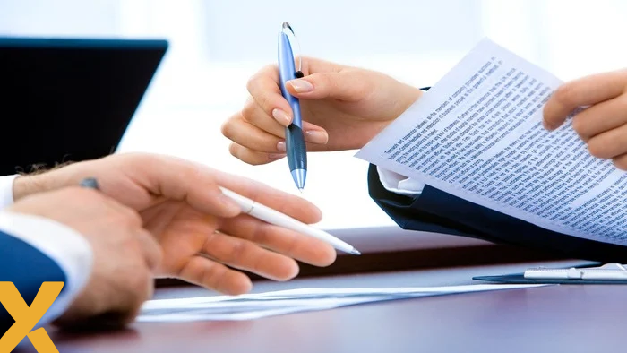 Close-up van handen die een document bespreken en ondertekenen aan een bureau, symbool voor zakelijke afspraken of contracten.