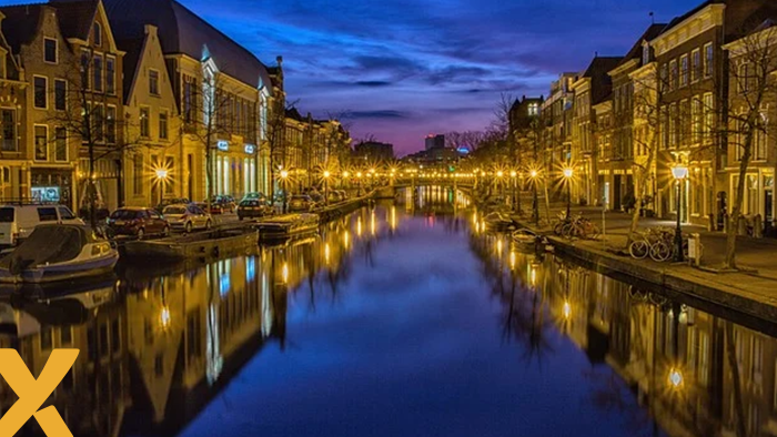 Verlichte grachten en historische gebouwen in Nederlandse binnenstad bij avondschemering.
