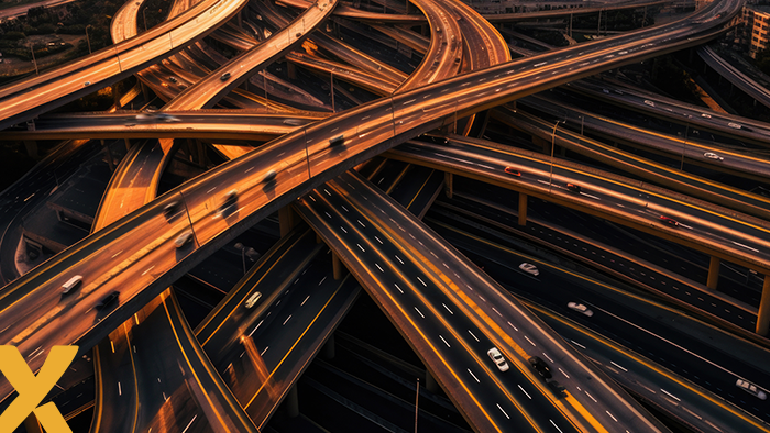 Drukke en complexe snelwegknooppunten bij zonsondergang met rijdend verkeer, symbool voor infrastructuur en flexibiliteit in netwerken.