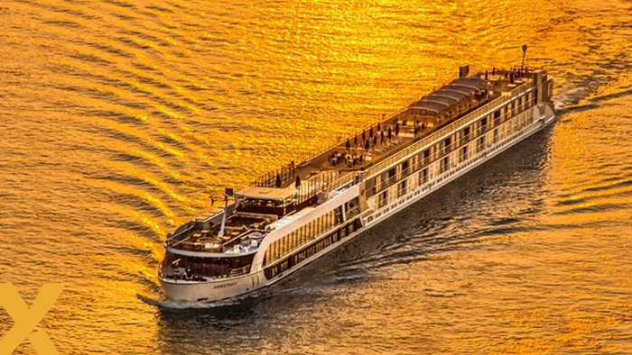 Riviercruiseboot vaart over goudkleurig water bij zonsondergang, met reflecties op het oppervlak.
