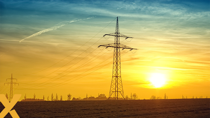 Hoogspanningsmast op een open veld bij zonsondergang, symbool voor samenwerking in energie-infrastructuur.