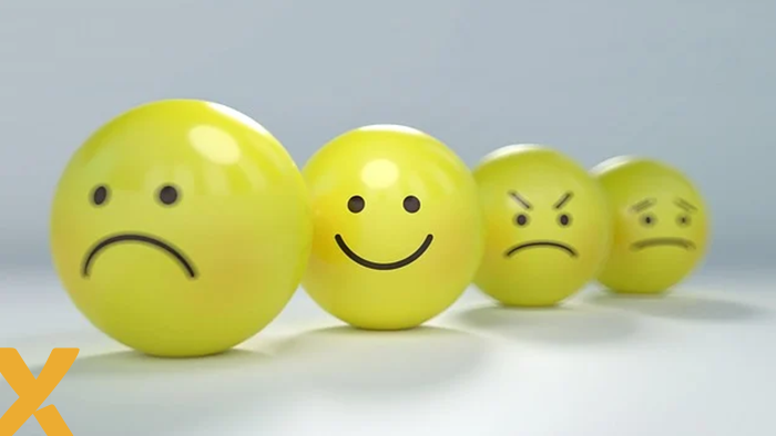 Vier gele emoticonballen met verschillende gezichtsuitdrukkingen, waaronder blij, verdrietig, boos en teleurgesteld.