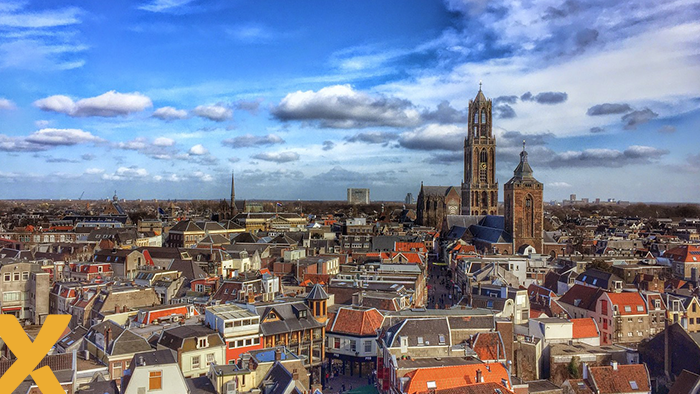 Panorama van de binnenstad van Utrecht met de Domtoren en traditionele Nederlandse gebouwen onder een deels bewolkte lucht.