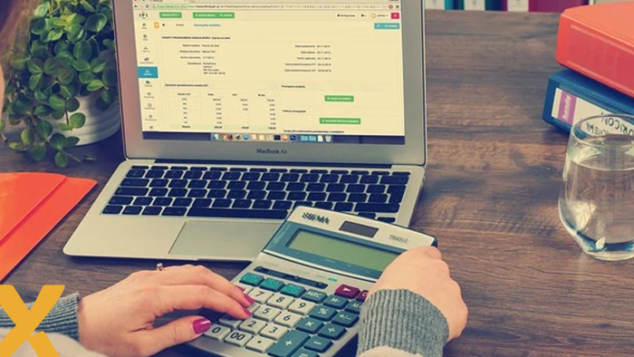 Persoon gebruikt rekenmachine voor financiële administratie met energierekening op laptopscherm.