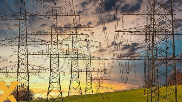 Hoogspanningsmasten en elektriciteitskabels in een open landschap bij zonsondergang, symbool voor het elektriciteitsnet en energie-infrastructuur.