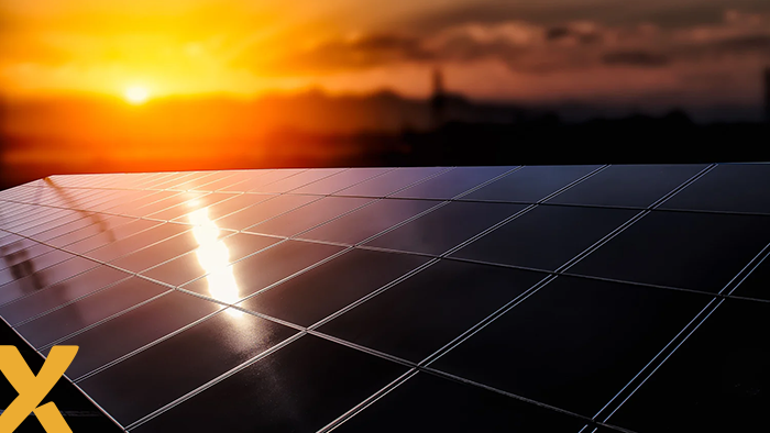Close-up van zonnepanelen met weerspiegeling van de ondergaande zon op het oppervlak.