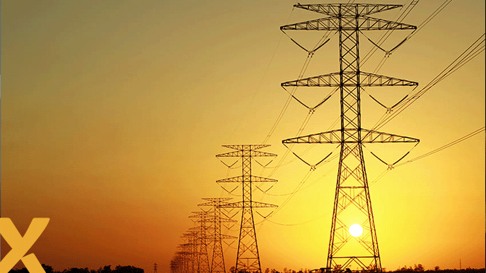 Rij hoogspanningsmasten in een landschap bij zonsondergang, symbool voor elektriciteitstransport en energie-infrastructuur.
