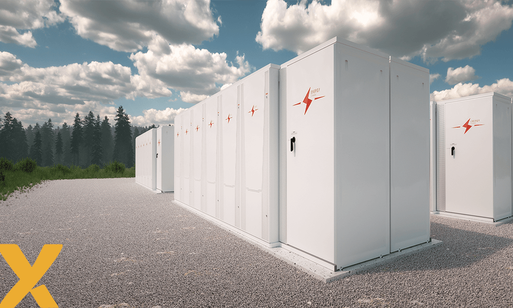 Witte batterijen voor energieopslag op een grindterrein onder een deels bewolkte lucht, omringd door groen landschap.