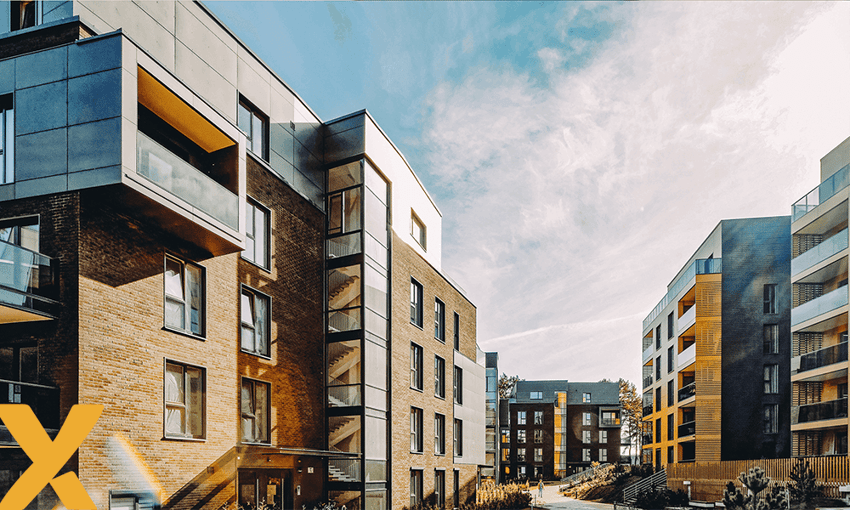 Een modern appartementencomplex met bakstenen en glazen gevels, gelegen in een open binnenhof met meerdere woongebouwen onder een heldere lucht.
