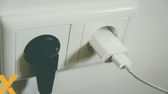 Dubbel wandcontactdoos met links een zwarte stekker en rechts een witte USB-oplader in het stopcontact.