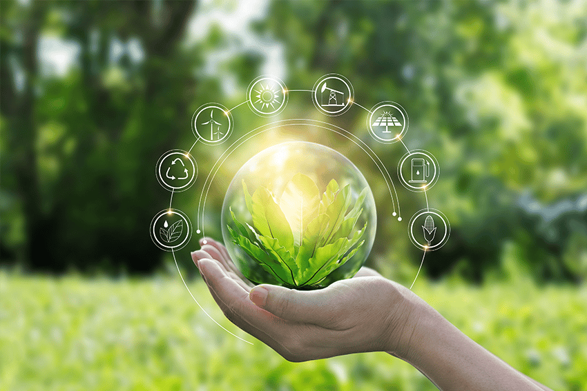 Hand die een glazen bol met groene bladeren vasthoudt, omringd door duurzame energie- en milieupictogrammen, tegen een natuurlijke, groene achtergrond.