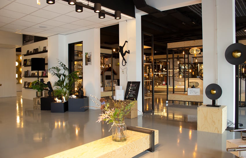 Modern ingerichte showroom met decoratieve verlichting, planten, designmeubels en opvallende kunstobjecten, waaronder klimmende aaplampen.