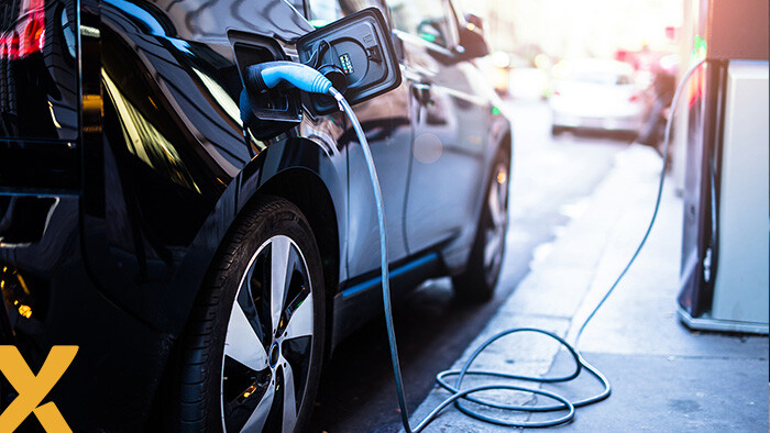 Elektrische auto wordt opgeladen bij een openbare laadpaal in een stedelijke omgeving.