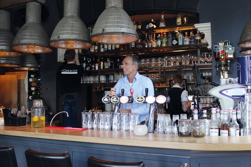 Gezellige bar van restaurant 't Gerecht in Heerenveen, met personeel achter de bar en een uitgebreide selectie drankflessen en glazen op de achtergrond.